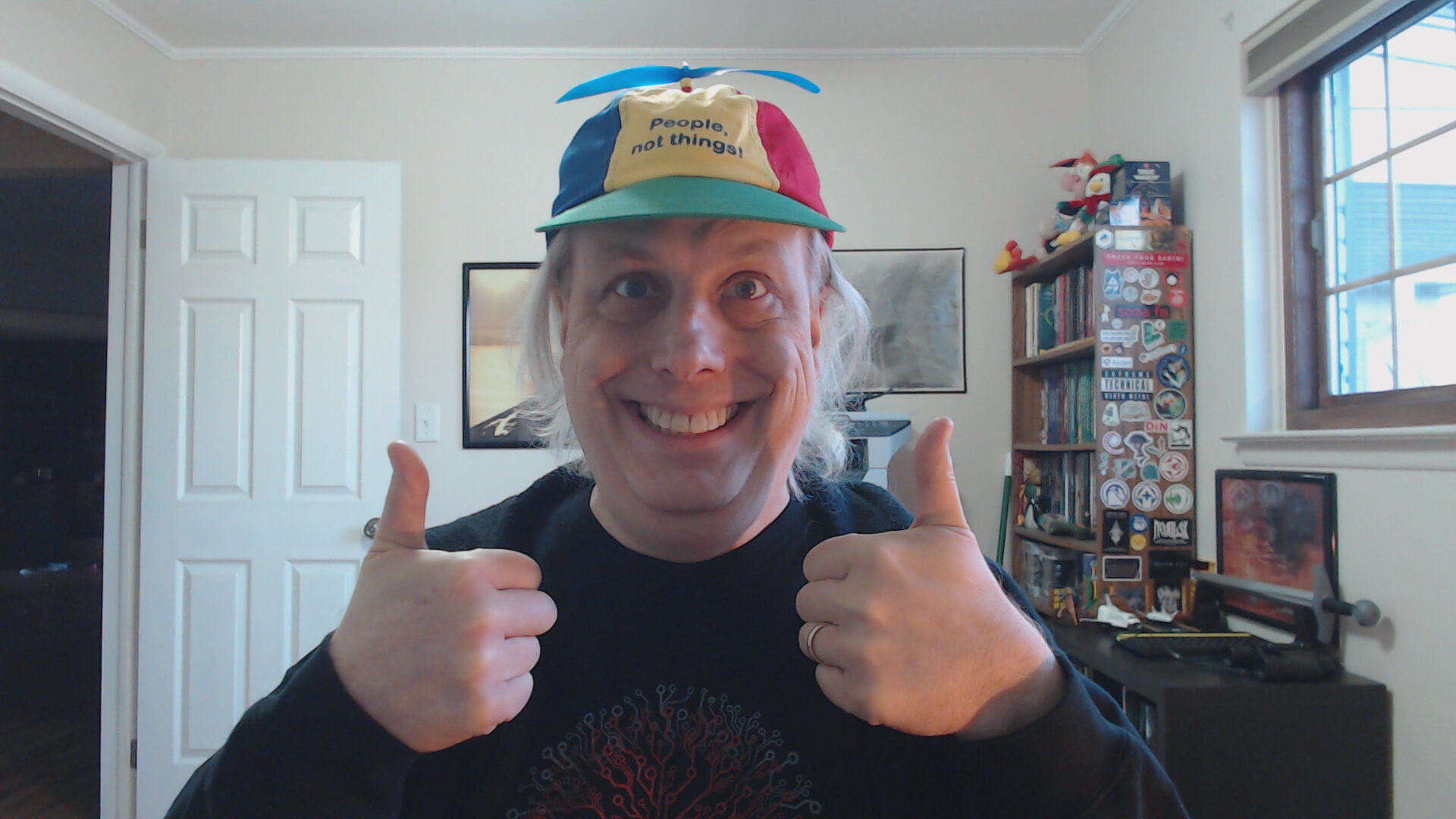 Me wearing a paneled baseball cap with different colors and a propeller on top that says 'People, not things!'
